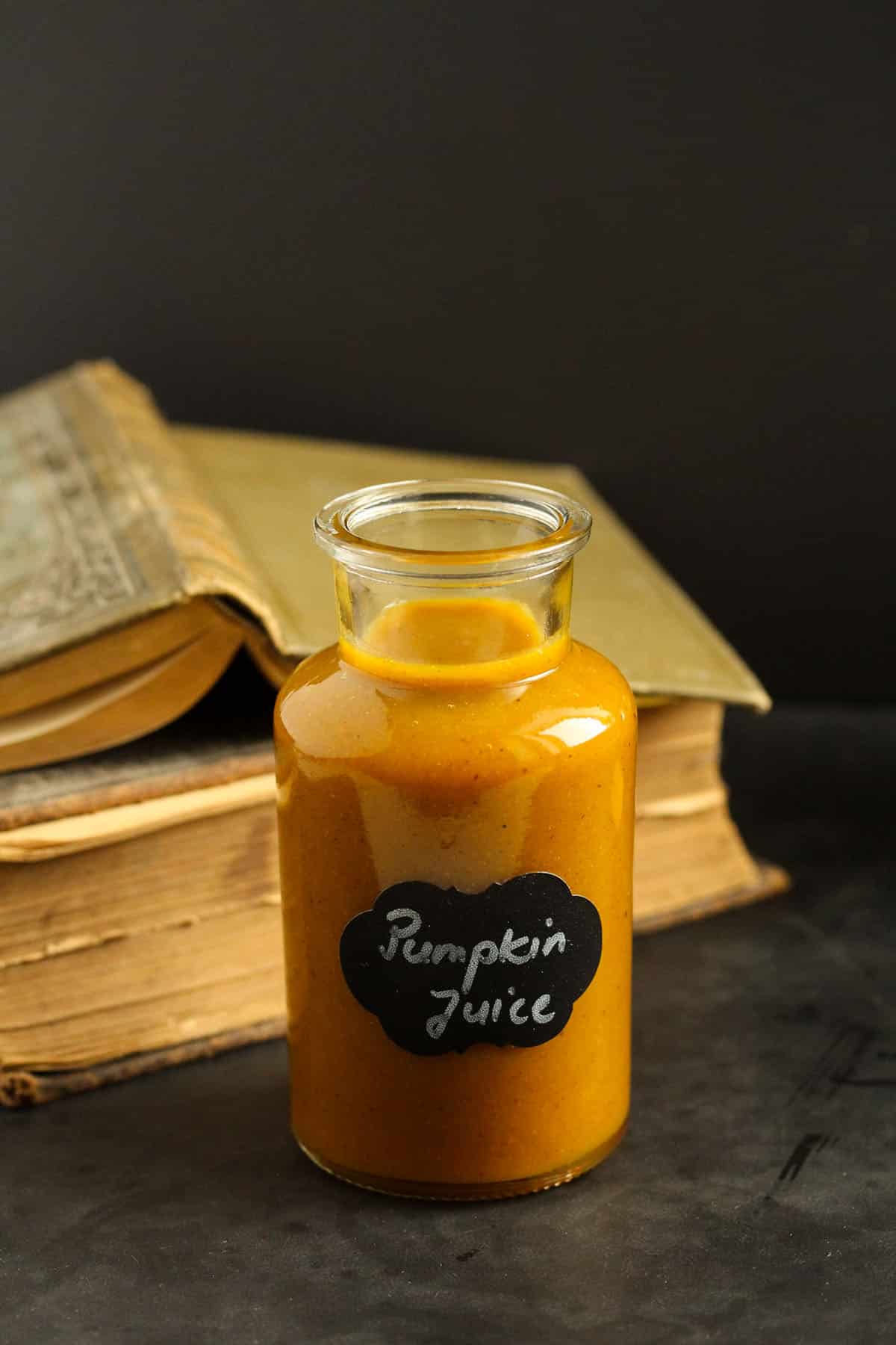 harry's pumpkin juice in a small labeled bottle and two old books behind it.
