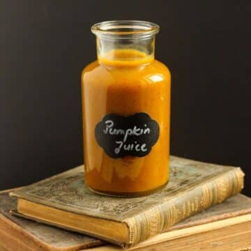 small bottle of harry potter pumpkin juice on a stack of old books.