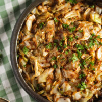 sauteed sweetheart cabbage with parsley and soy sauce in a bowl on a green kitchen cloth.