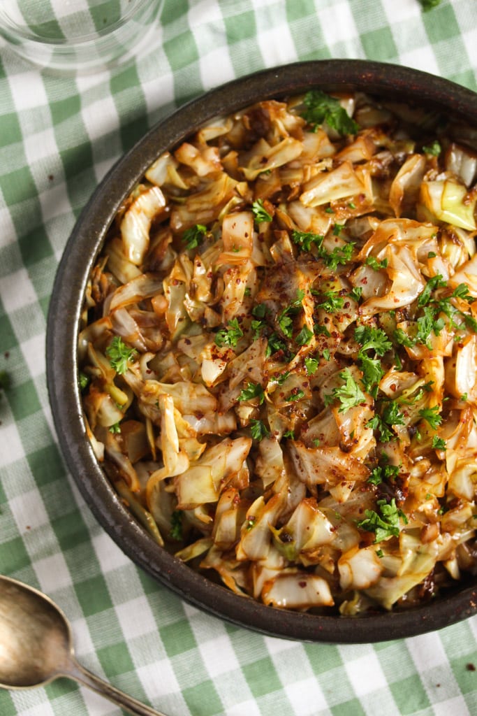 sauteed sweetheart cabbage with parsley and soy sauce in a bowl on a green kitchen cloth.