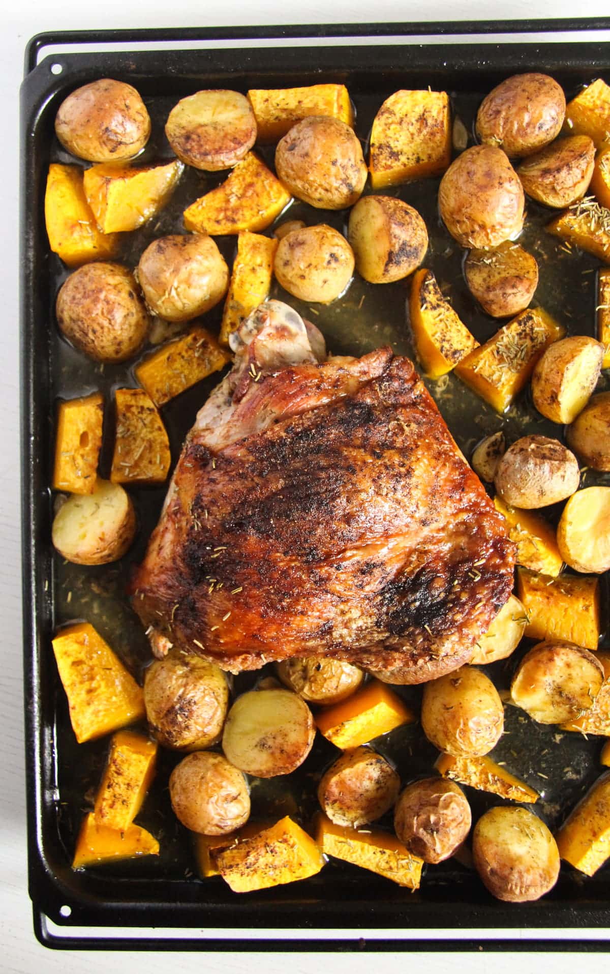 overhead view of large sheet pan with roasted turkey thigh, potatoes and pumpkin.