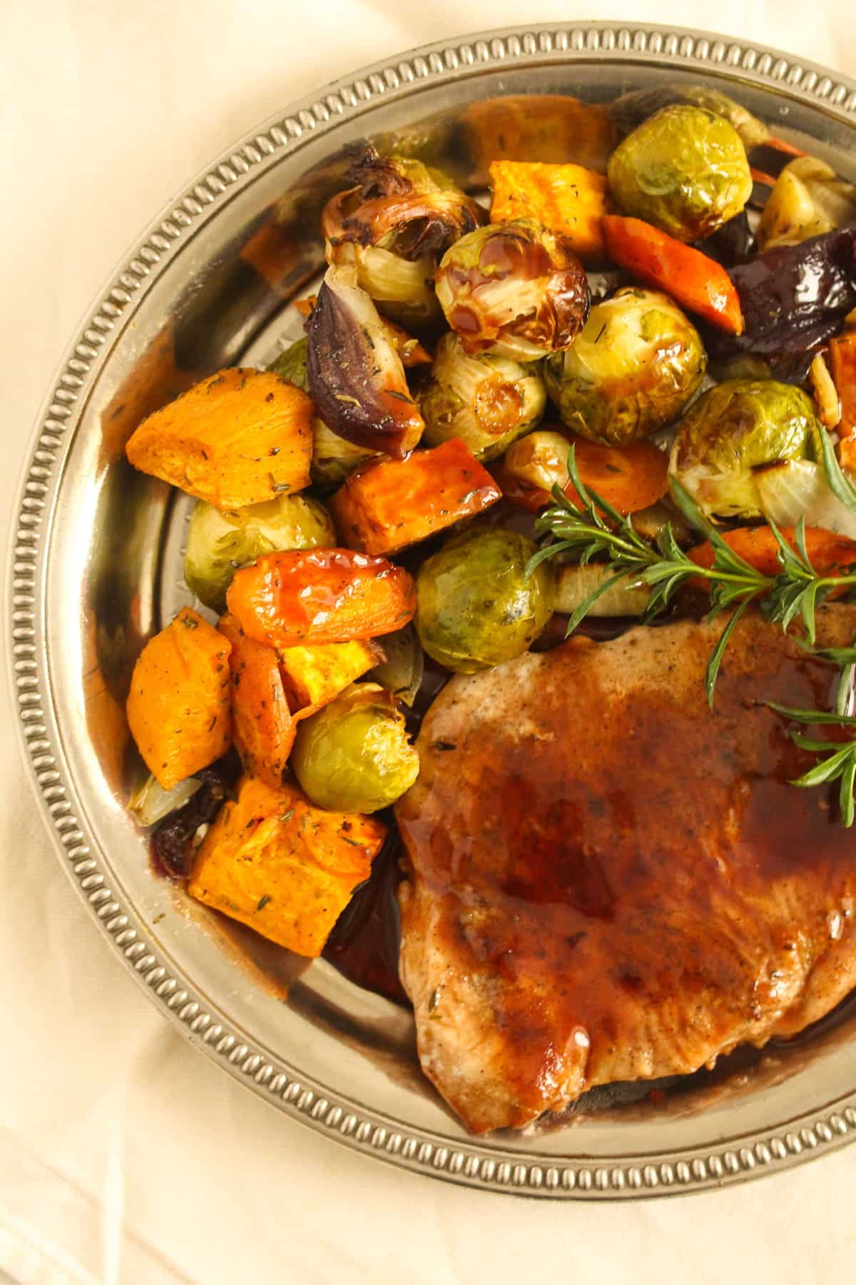 roasted veggies on a plate with turkey cutlet and sauce.