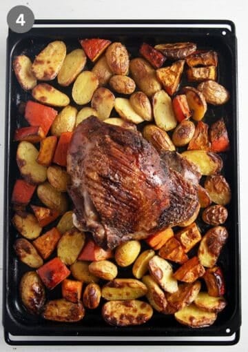 baked turkey thigh, potatoes and pumpkin pieces on a baking sheet.