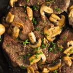 close up veal cutlets with mushrooms and parsley in a pan.