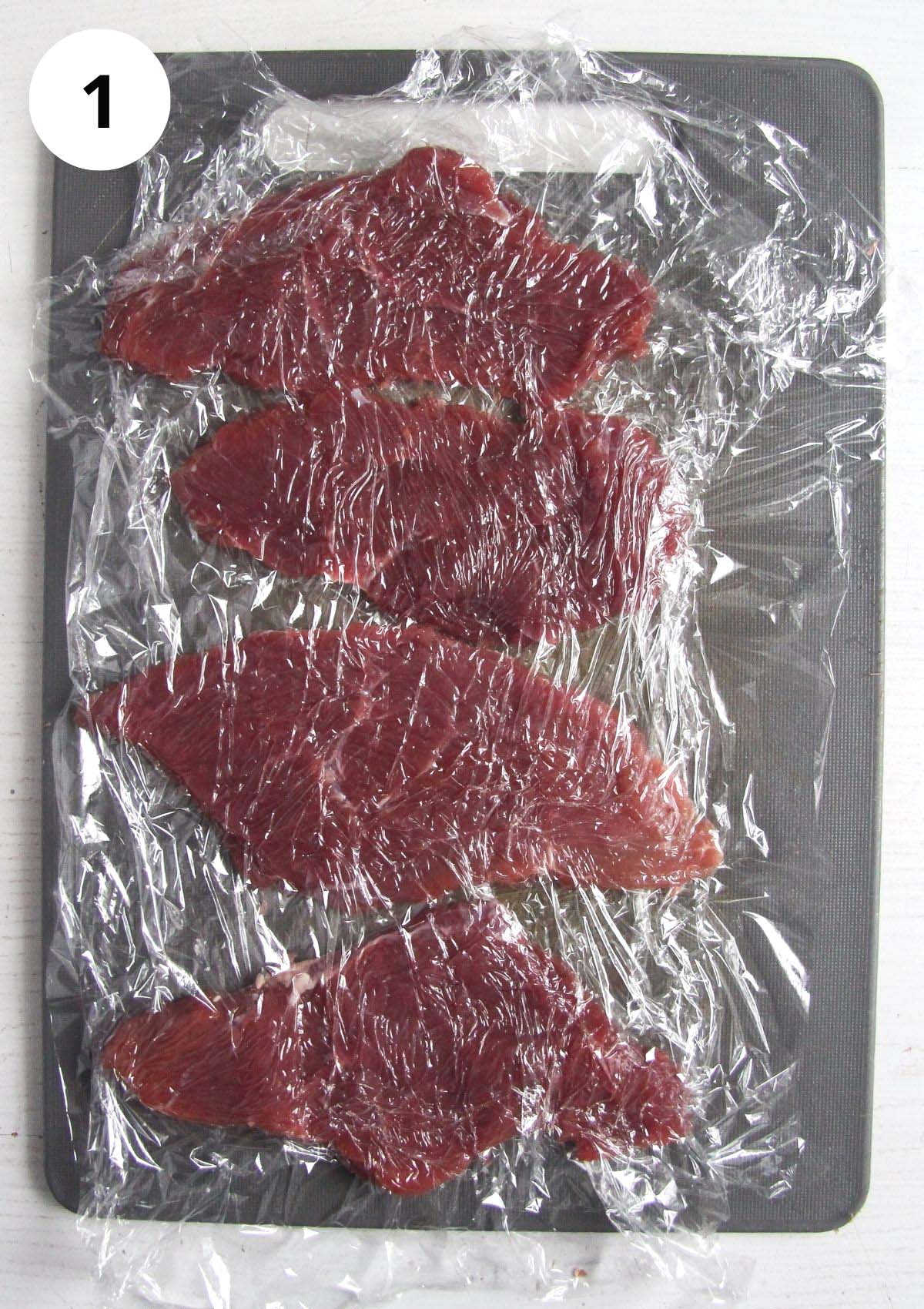 slices of raw veal pounded between sheets of cling film.