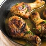 three stove top chicken drumsticks sprinkled with parsley.