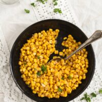 cooked corn kernels on a black plate.