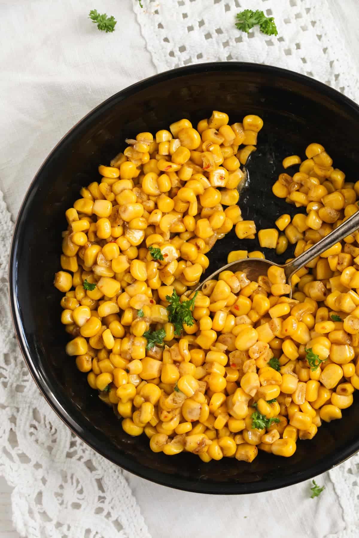 cooked frozen corn kernels in a black bowl.