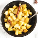 stewed pears with cinnamon and star anise in a black bowl.