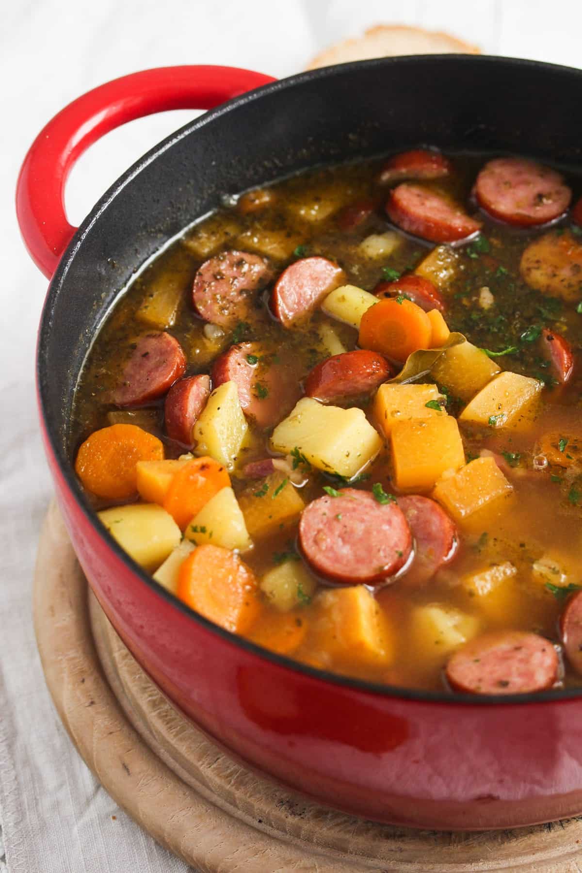 red pot with soup with swede, carrots and sausages.