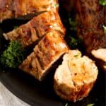 sliced apricot glazed pork tenderloin on a small black plate.