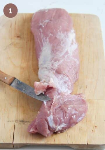 removing fat from a pork tenderloin with a small knife.