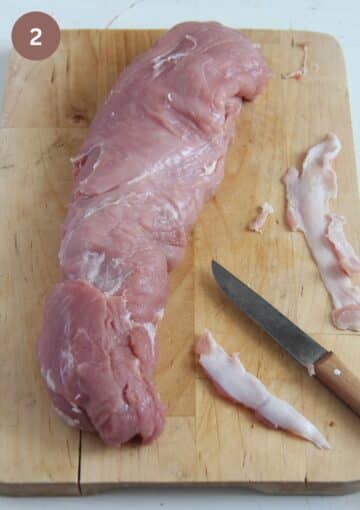 removing silver skin from a pork tenderloin with a small knife.