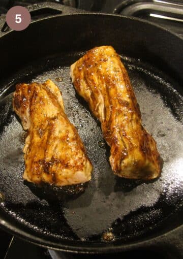 searing two pieces of pork in a cast iron skillet.