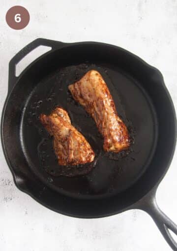 two small pork tenderloins glazed with jam in a cast iron skillet.