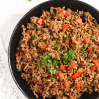 cooked minced beef in a bowl with peppers and parsley.