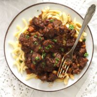 authentic german goulash served with spaetzle on a small plate with a vintage fork.