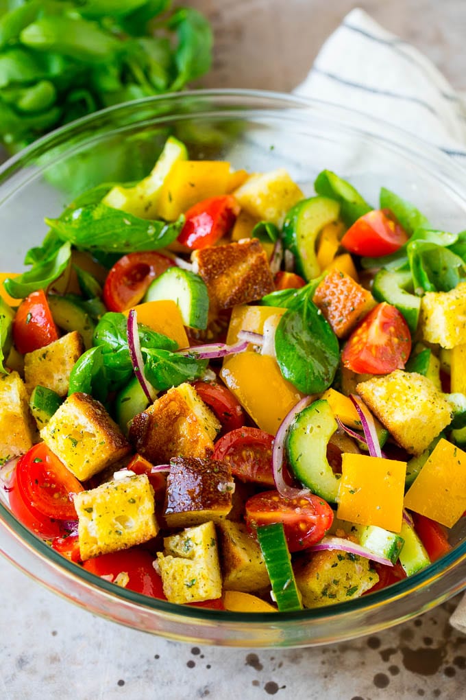 colorful panzanella salad with herbs in a bowl close up.