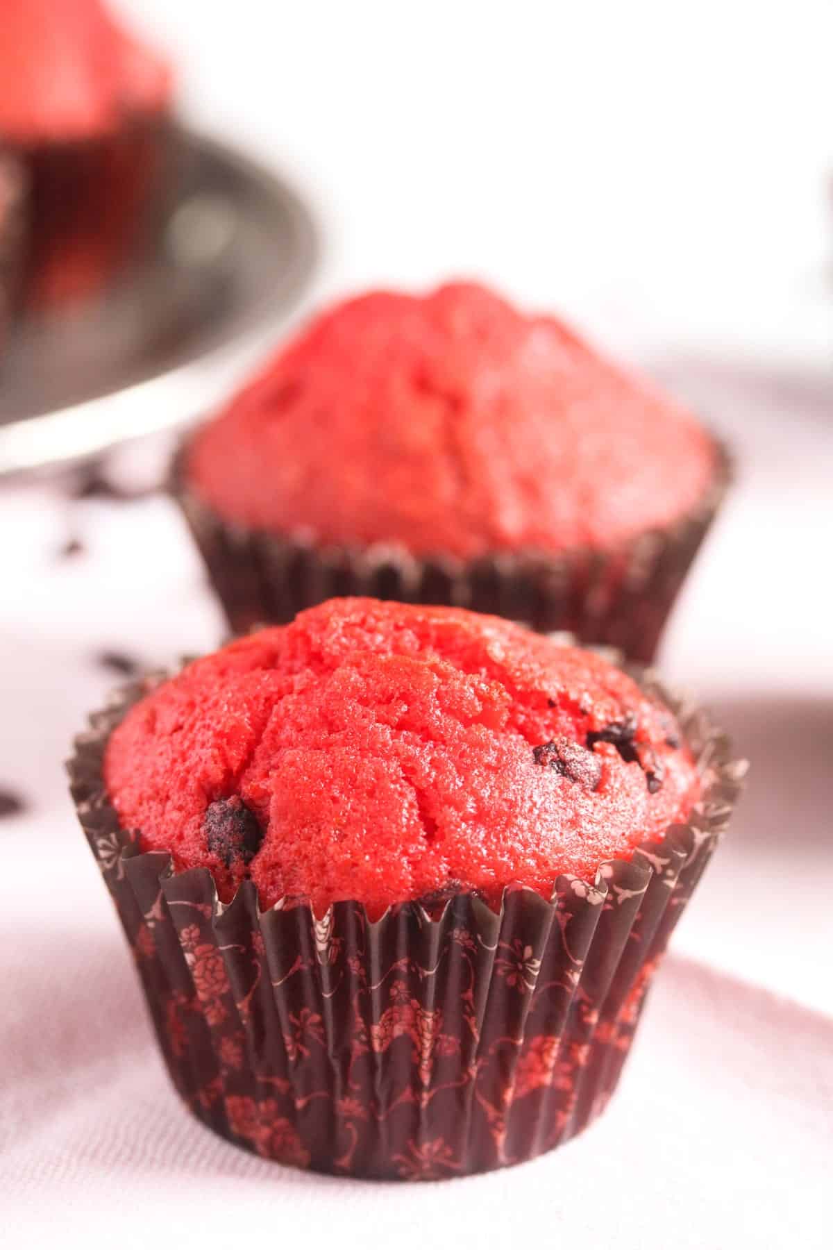 two red colored muffins with chocolate chips.