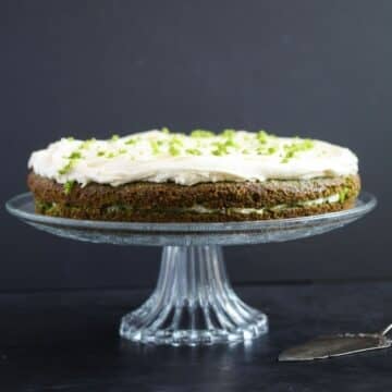 spinach cake frosted with cream cheese white chocolate frosting on a high platter.