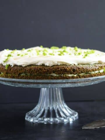 spinach cake frosted with cream cheese white chocolate frosting on a high platter.