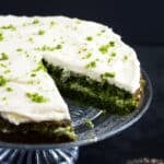 cut spinach cake frosted with cream cheese on a platter.