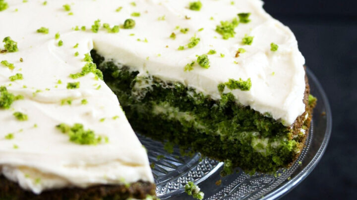 cut spinach cake frosted with cream cheese on a platter.