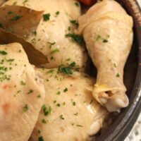 close up of boiled chicken thighs and drumsticks in a brown bowl.