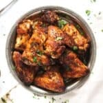 baked whole chicken wings on a silver plate sprinkled with parsley.