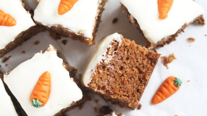 many squares of frosted cake decorated with marzipan carrots.