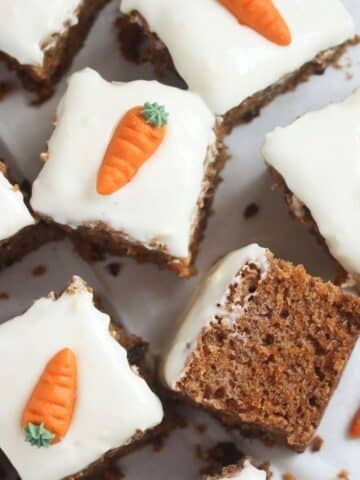 carrot cake traybake cut into squares frosted and decorated with marzipan carrots.