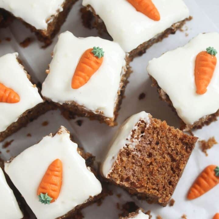 carrot cake traybake cut into squares frosted and decorated with marzipan carrots.