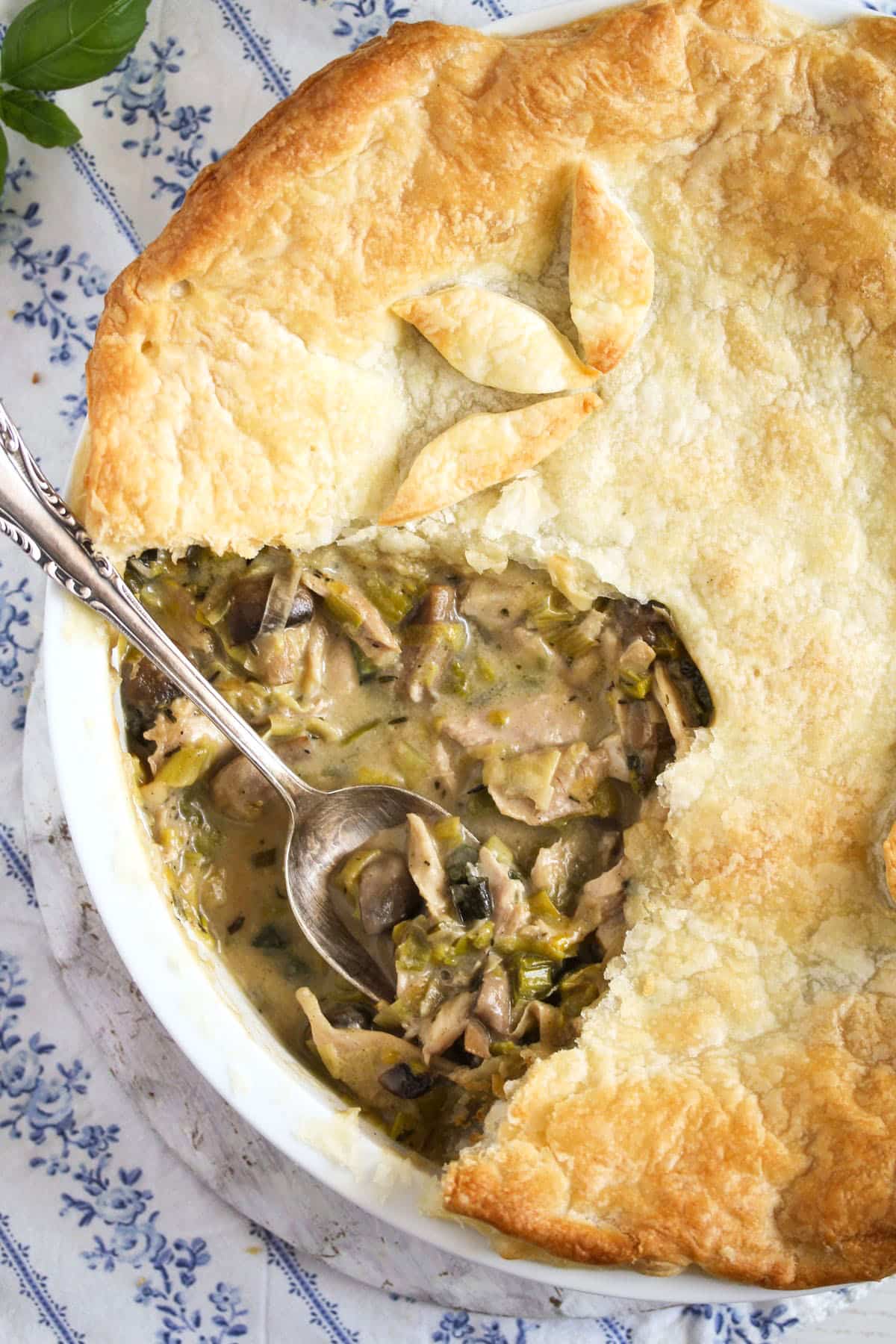 overhead view of chicken pie with puff pastry and a spoon in it.