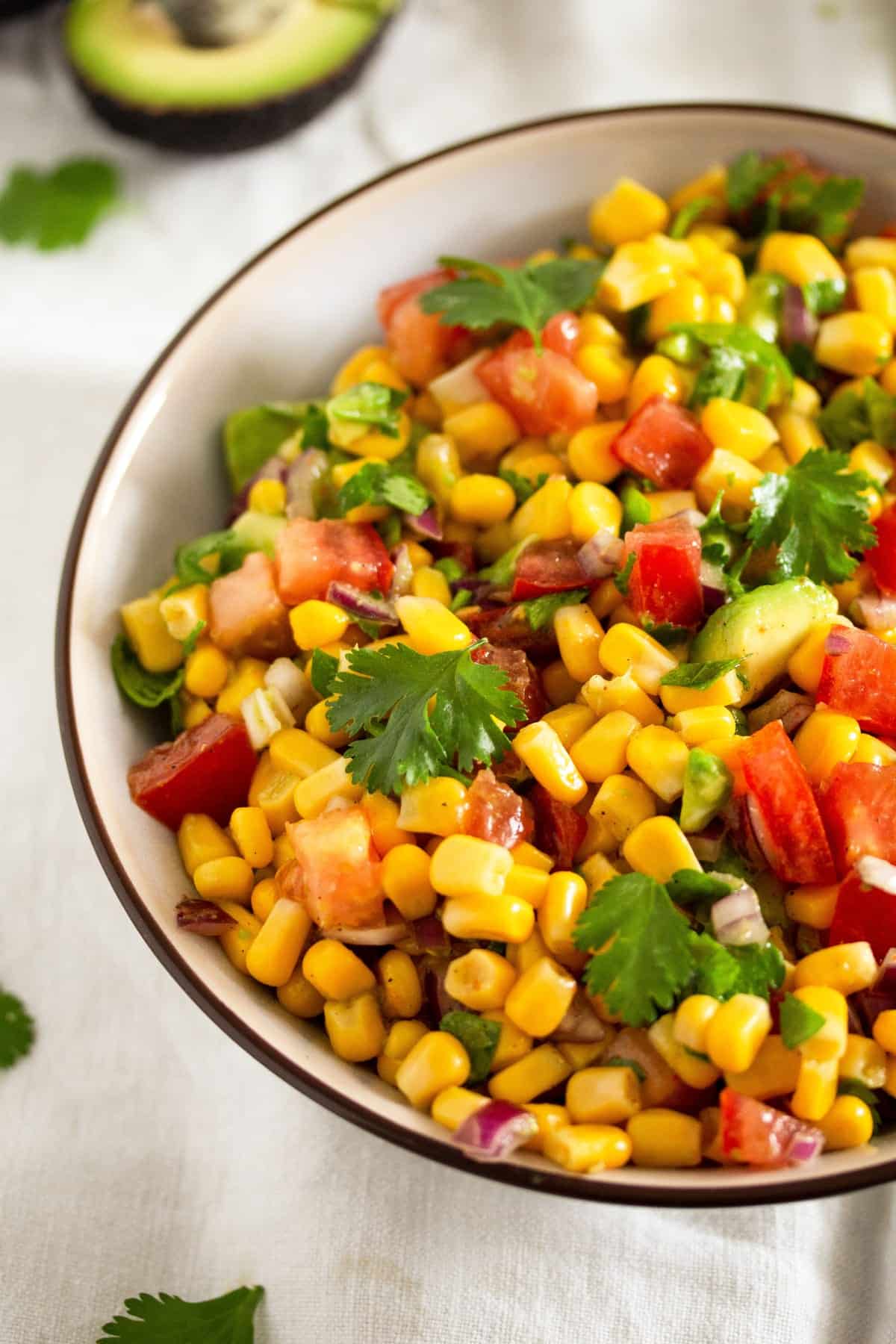 small bowl with colorful mexican salad with corn, avocado and tomatoes.