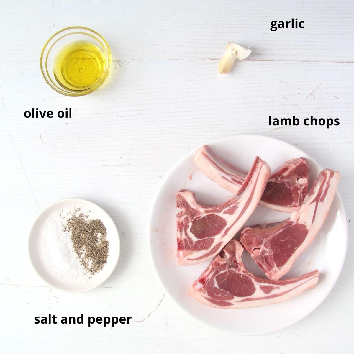raw lamb chops on a plate, garlic cloves and bowls with oil and spices.