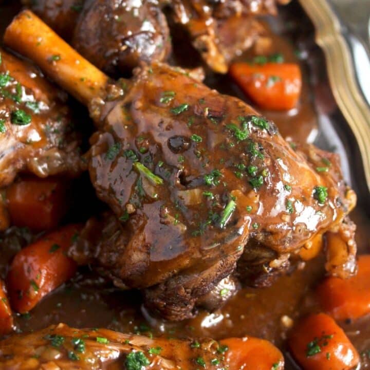 close up one lamb shank covered with glossy gravy.