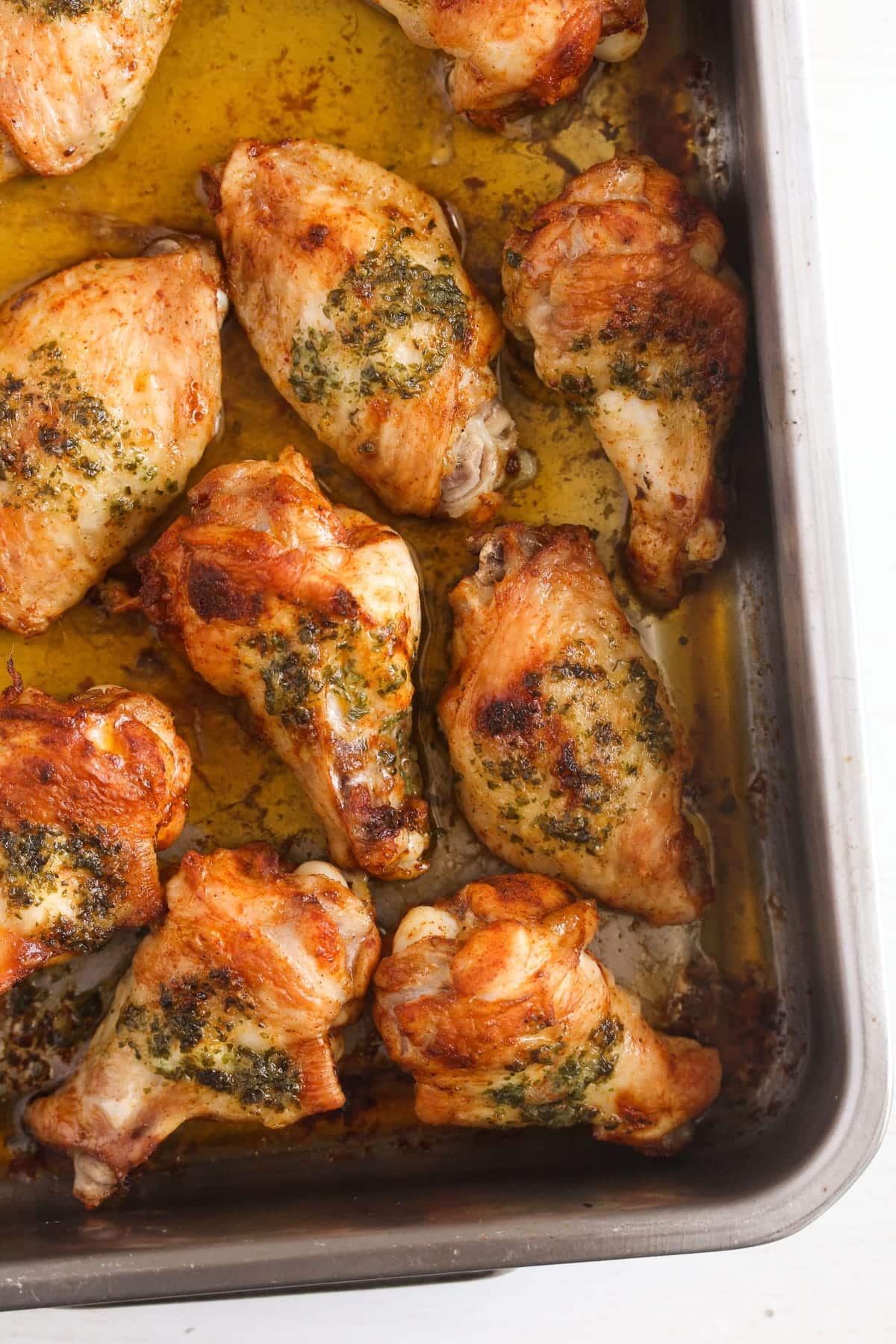 many golden roasted buttered wings in a baking dish.