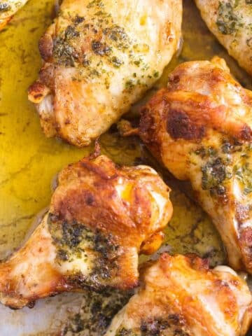 close up of several golden buttered chicken wings with melted butter around.