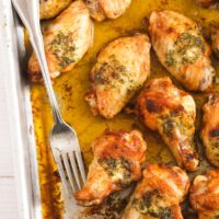 close image of a baking tin with juicy chicken wings and a fork.
