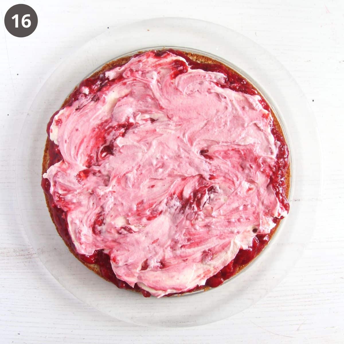 spreading raspberry sauce and frosting on a layer of cake.