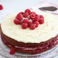 layered raspberry cake with white chocolate and fresh berries on top.