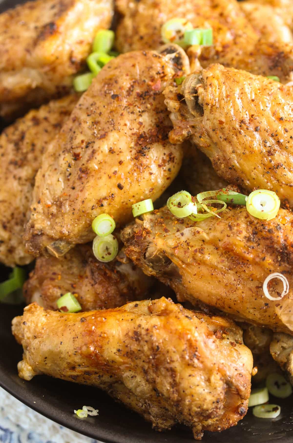 close up crispy wings sprinkled with spring onions.