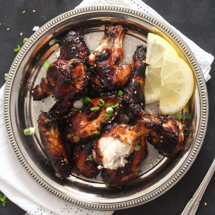 silver plate with soy garlic chicken wings with lemon wedges.