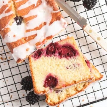 sliced blackberry lemon bread on a wire rack with a small knife.