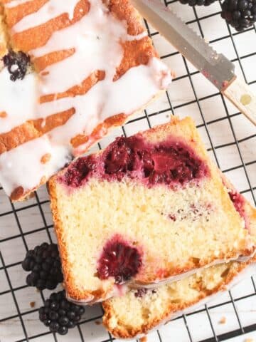 sliced blackberry lemon bread on a wire rack with a small knife.