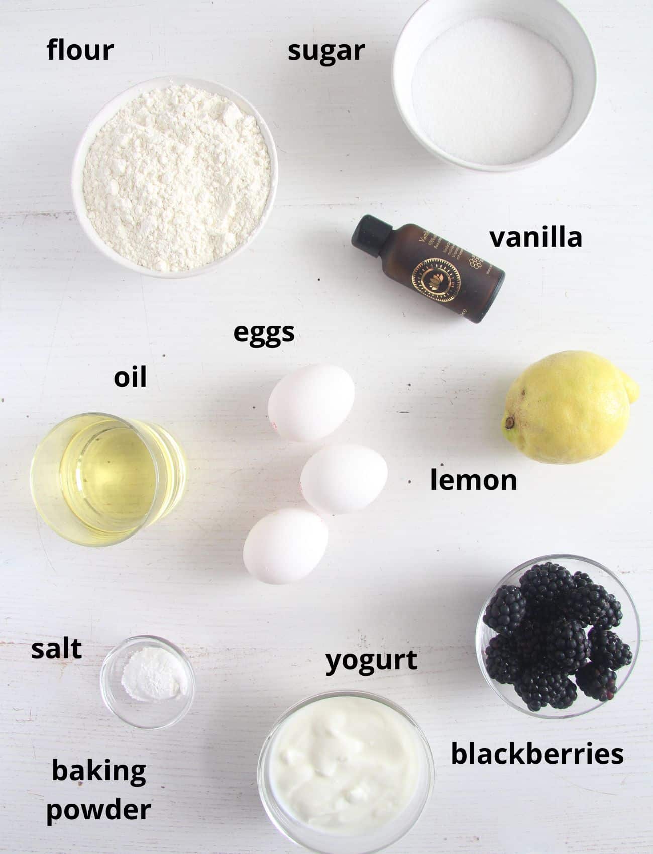 listed ingredients for making bread with blackberries and lemon on the table.