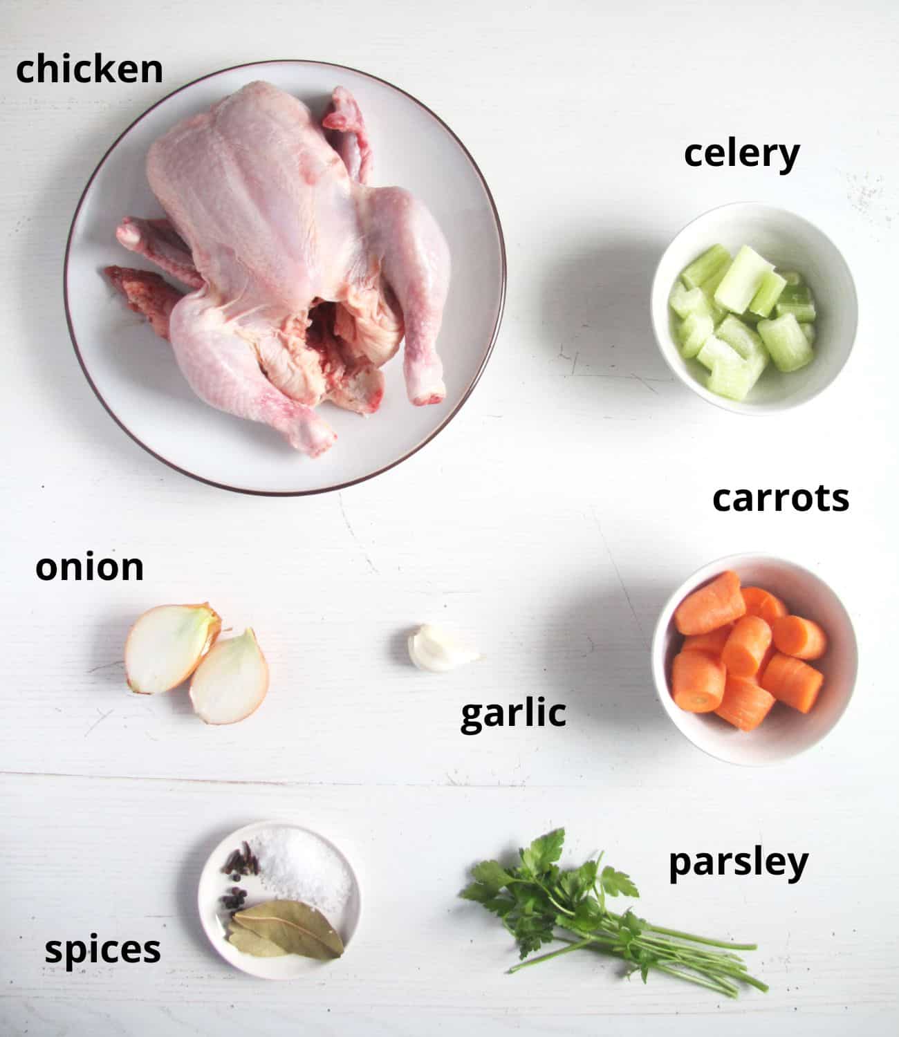 bowls with whole chicken, celery, onion, carrots, parsley and spices.