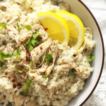 close up boiled chicken and rice with lemon wedges.