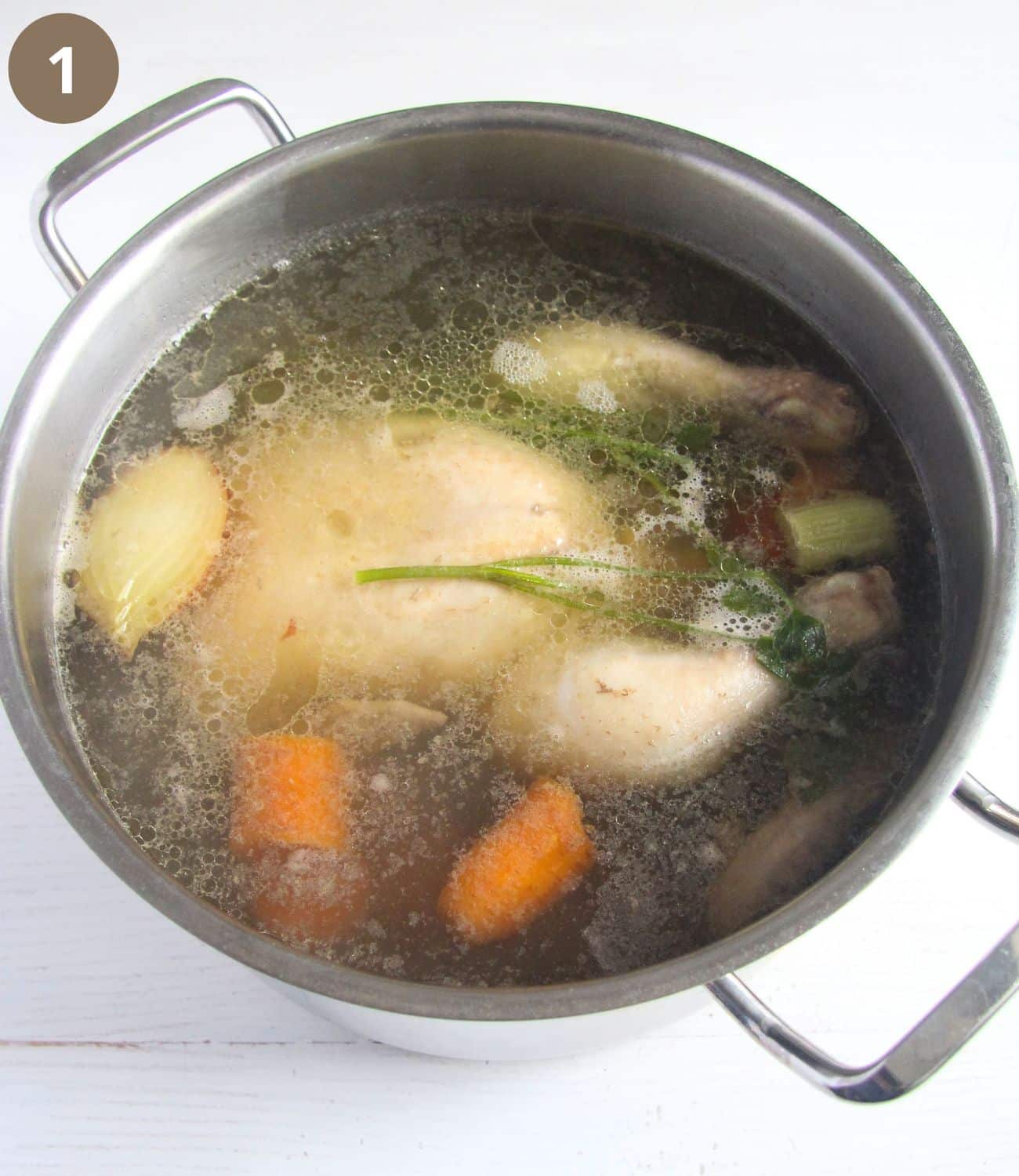 cooked whole chicken with carrots in a pot.