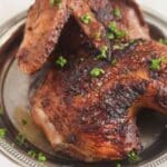 grilled chicken half with char marks on a platter.